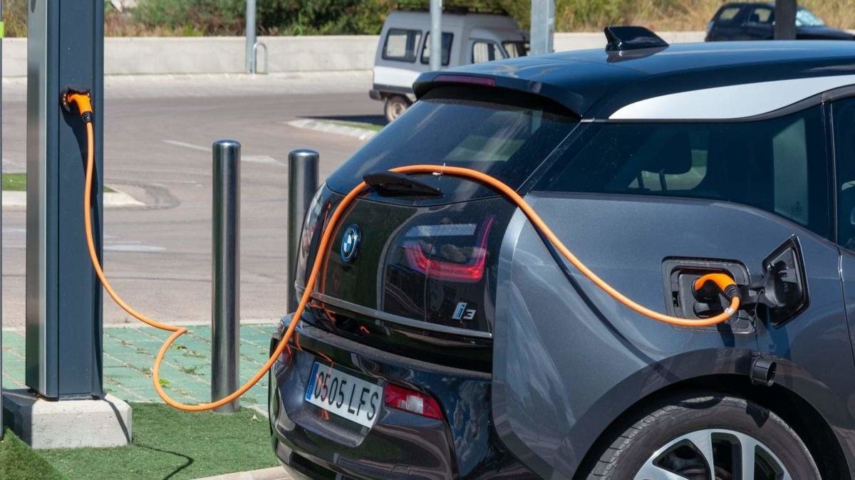 Un coche eléctrico carga su batería en un aparcamiento - Foto de 123FR/Nemesio Jiménez